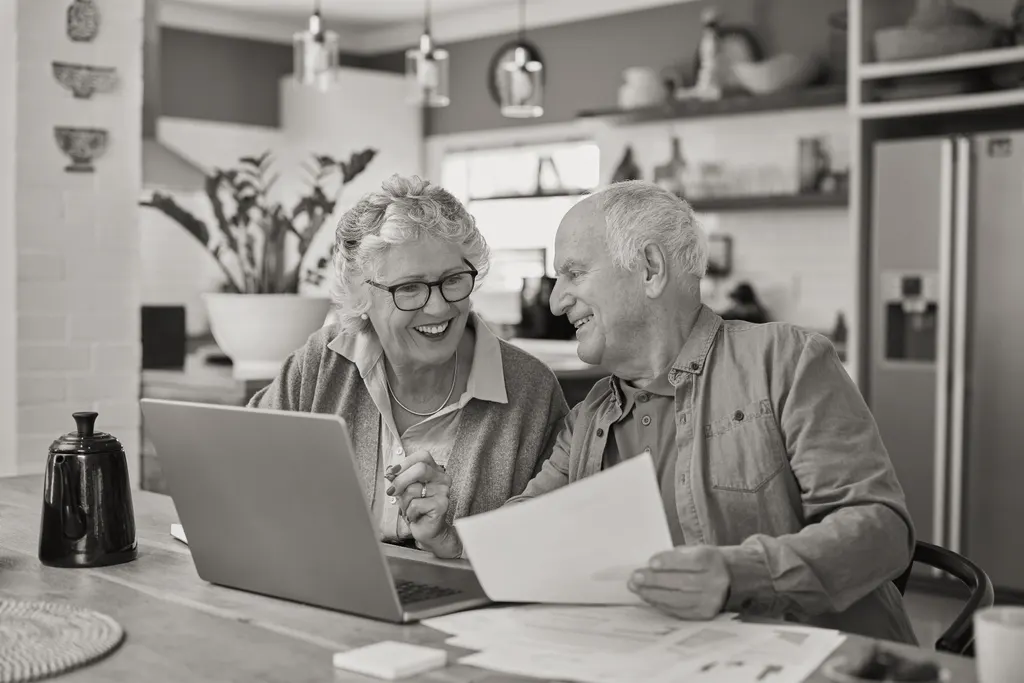 Older couple reviewing documents and a laptop at home while planning their affairs